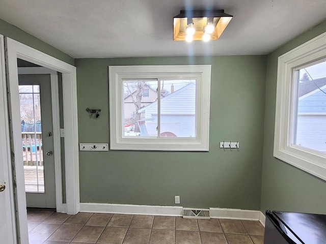 unfurnished dining area featuring dark tile patterned flooring