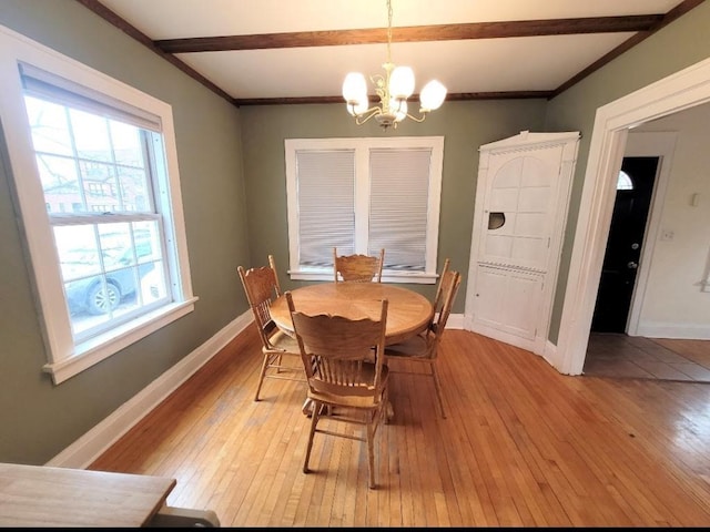 dining area featuring beamed ceiling, a notable chandelier, crown molding, and light wood-type flooring