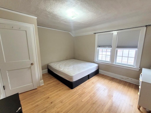 bedroom with ornamental molding, light hardwood / wood-style flooring, and a textured ceiling