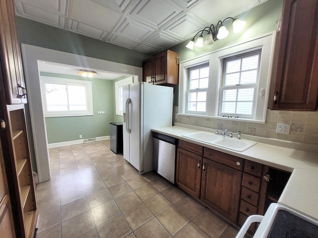 kitchen featuring white refrigerator with ice dispenser, dishwasher, sink, and decorative backsplash