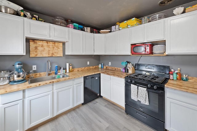 kitchen featuring white cabinetry, butcher block counters, sink, black appliances, and light wood-type flooring