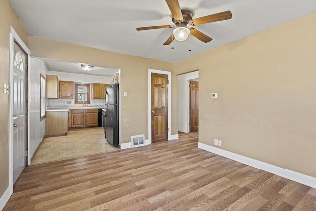 kitchen with black refrigerator, ceiling fan, and light wood-type flooring