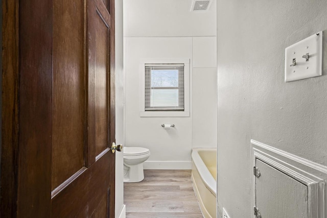 bathroom featuring toilet, a bathing tub, and hardwood / wood-style floors