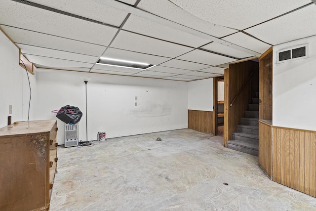 basement with wooden walls and a drop ceiling