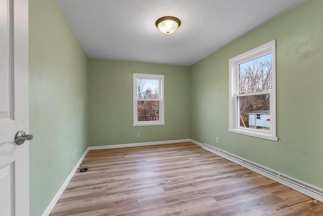 unfurnished room with a baseboard radiator and light wood-type flooring