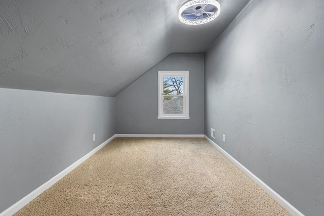 additional living space featuring carpet floors, vaulted ceiling, and a textured ceiling