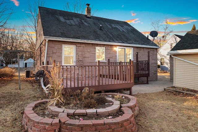 back house at dusk featuring central AC and a deck