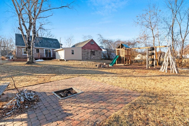 view of jungle gym featuring a patio, an outbuilding, and an outdoor fire pit