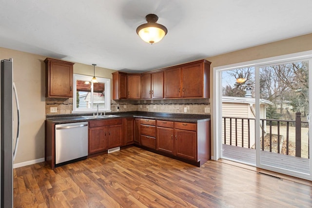 kitchen featuring decorative light fixtures, sink, stainless steel appliances, plenty of natural light, and dark wood-type flooring