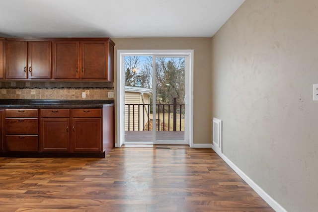 kitchen featuring backsplash, dark hardwood / wood-style floors, and dark stone counters