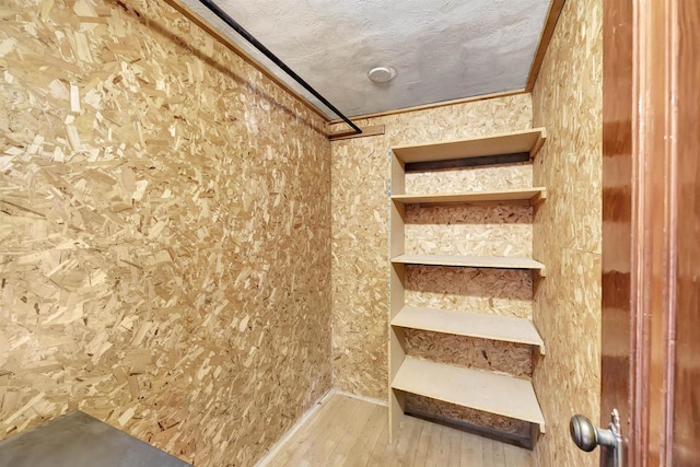 stairway featuring wood-type flooring, ornamental molding, and a textured ceiling