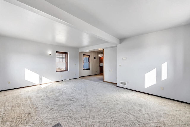 carpeted empty room with beamed ceiling