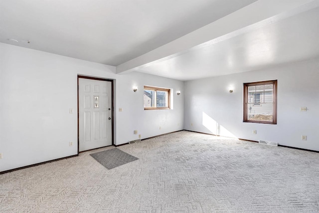 empty room featuring beam ceiling and light carpet