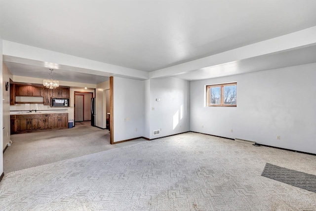 unfurnished living room with an inviting chandelier and light carpet