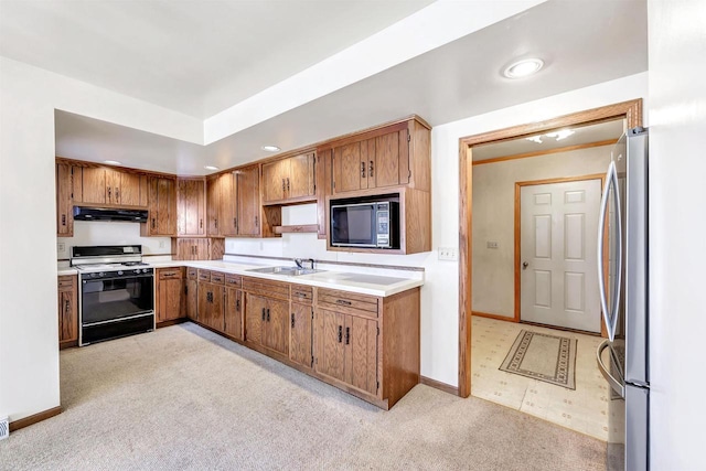 kitchen featuring range with gas stovetop, stainless steel refrigerator, black microwave, sink, and light carpet