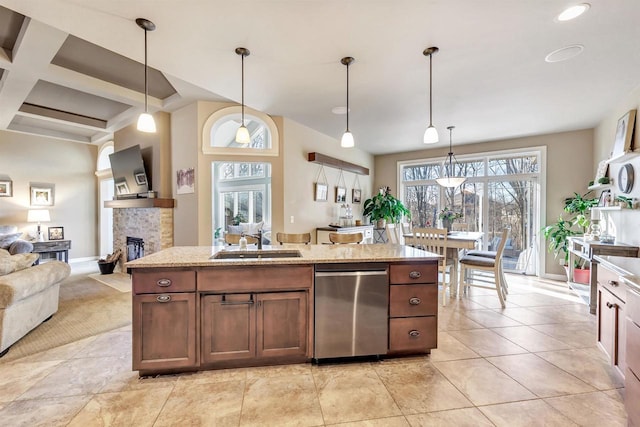 kitchen with pendant lighting, sink, stainless steel dishwasher, and a stone fireplace