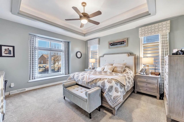 carpeted bedroom featuring a raised ceiling and ceiling fan