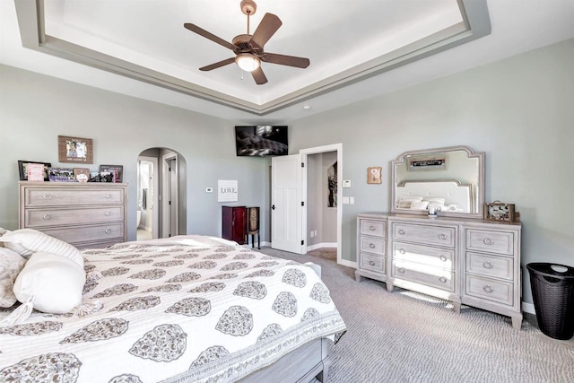 carpeted bedroom with a tray ceiling and ceiling fan