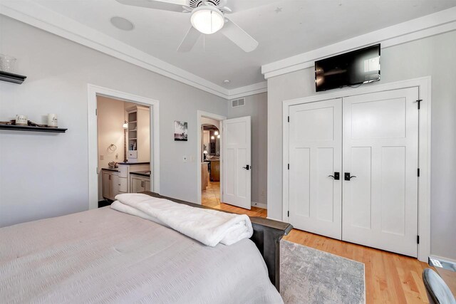 bedroom with ensuite bathroom, light hardwood / wood-style flooring, ornamental molding, a closet, and ceiling fan