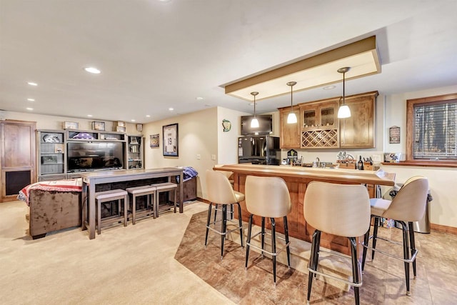 bar featuring pendant lighting, light colored carpet, and black fridge