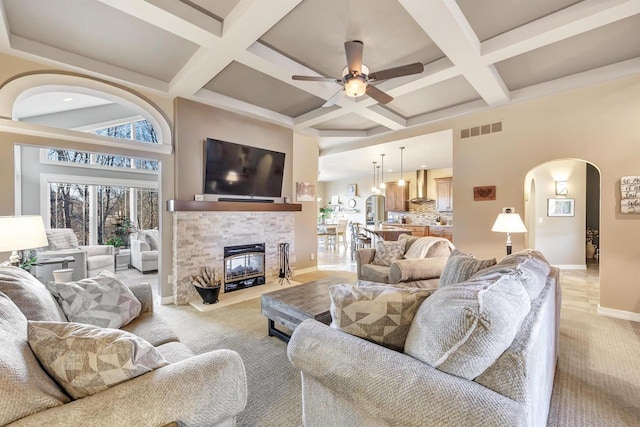 carpeted living room featuring coffered ceiling, a fireplace, beamed ceiling, and ceiling fan