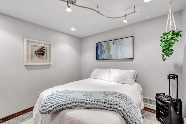 bedroom with wood-type flooring and rail lighting