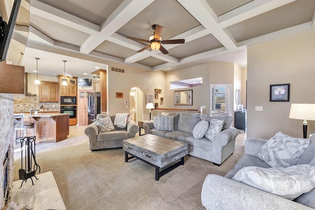 living room with beamed ceiling, coffered ceiling, and ceiling fan