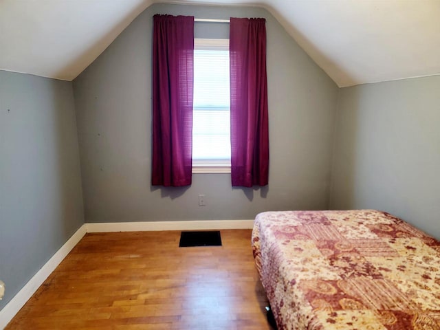 bedroom with vaulted ceiling and light hardwood / wood-style flooring