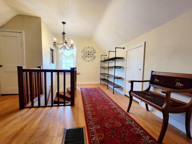 corridor with lofted ceiling, light hardwood / wood-style floors, and a chandelier