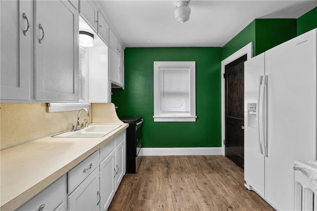 kitchen featuring white cabinetry, radiator heating unit, white refrigerator with ice dispenser, and sink