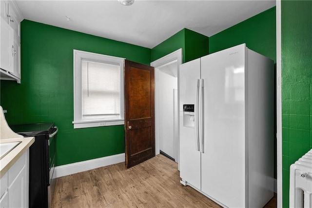 kitchen featuring radiator, white cabinetry, white refrigerator with ice dispenser, black range with electric cooktop, and light hardwood / wood-style flooring