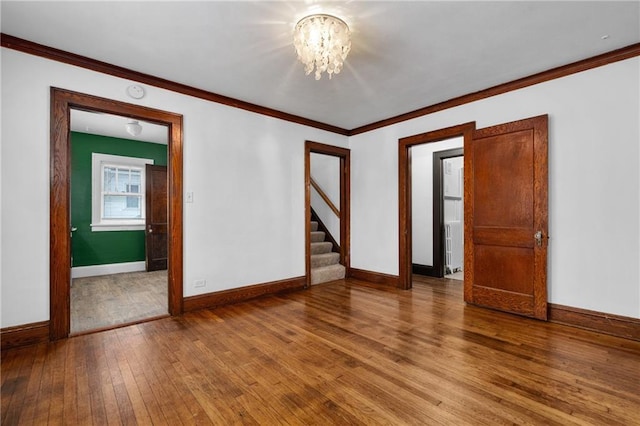 unfurnished room with ornamental molding, a chandelier, and hardwood / wood-style floors