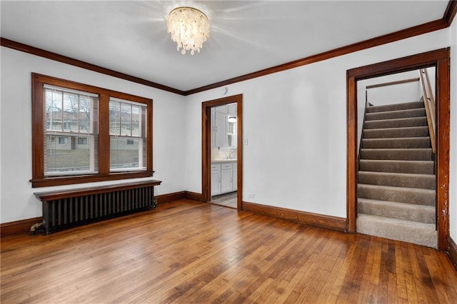 unfurnished room with an inviting chandelier, radiator, wood-type flooring, and ornamental molding