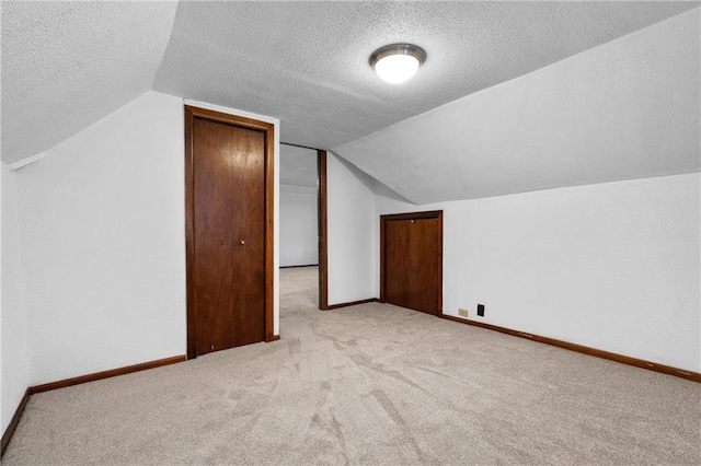 additional living space with light carpet, lofted ceiling, and a textured ceiling