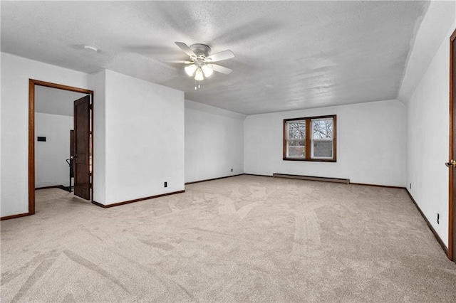 spare room featuring a baseboard heating unit, light colored carpet, a textured ceiling, and ceiling fan