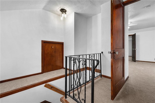 stairway with vaulted ceiling, carpet, and a textured ceiling