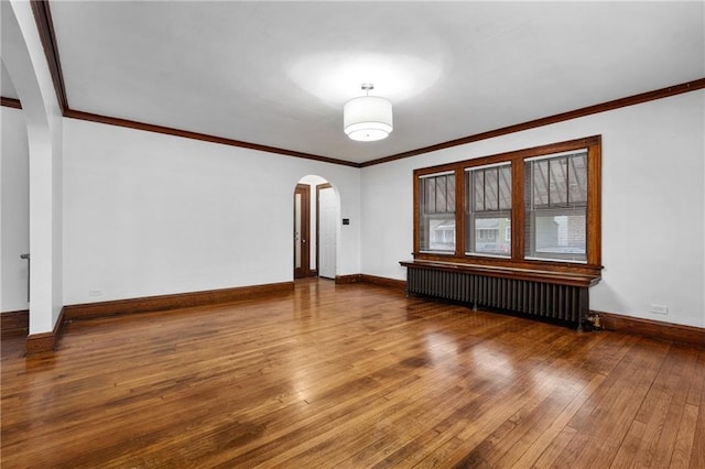 empty room with hardwood / wood-style floors, radiator heating unit, and ornamental molding