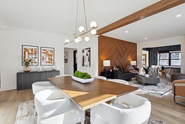 dining area featuring an inviting chandelier, beam ceiling, and light hardwood / wood-style flooring