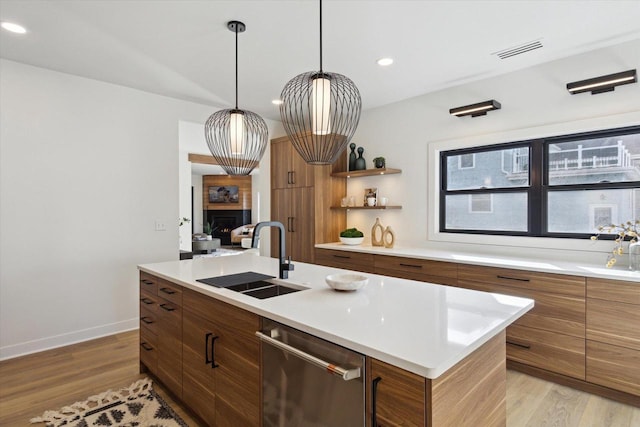 kitchen with stainless steel dishwasher, sink, a center island with sink, and light hardwood / wood-style floors