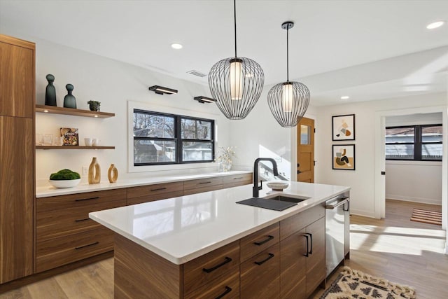 kitchen featuring plenty of natural light, a kitchen island with sink, sink, and light wood-type flooring