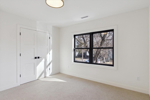 unfurnished bedroom with light colored carpet and a closet