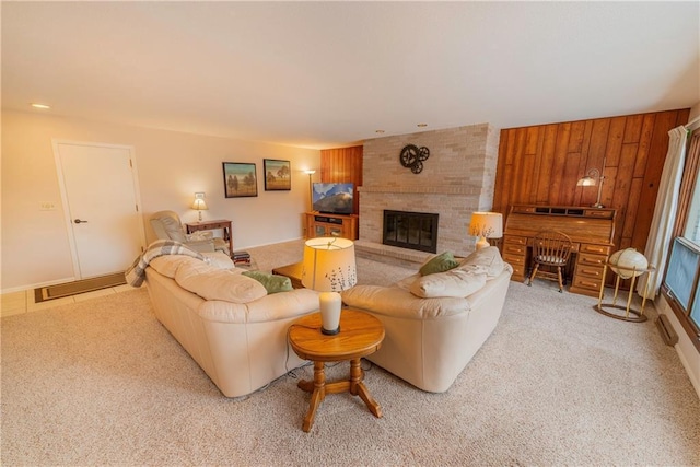 living room with light colored carpet, wooden walls, and a brick fireplace