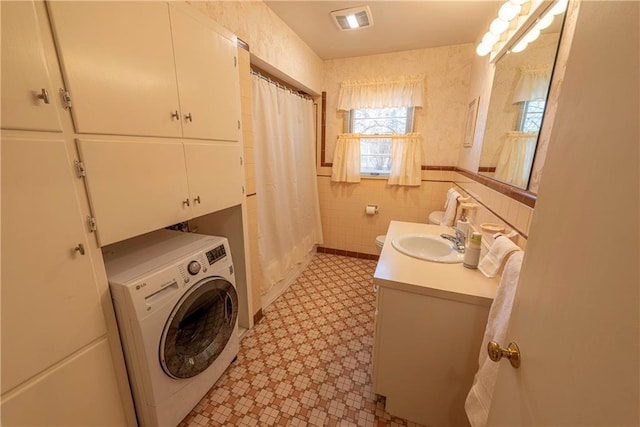 clothes washing area featuring tile walls, sink, and washer / dryer