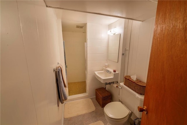 bathroom with tiled shower, sink, and toilet