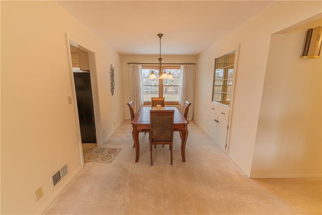 carpeted dining space featuring an inviting chandelier