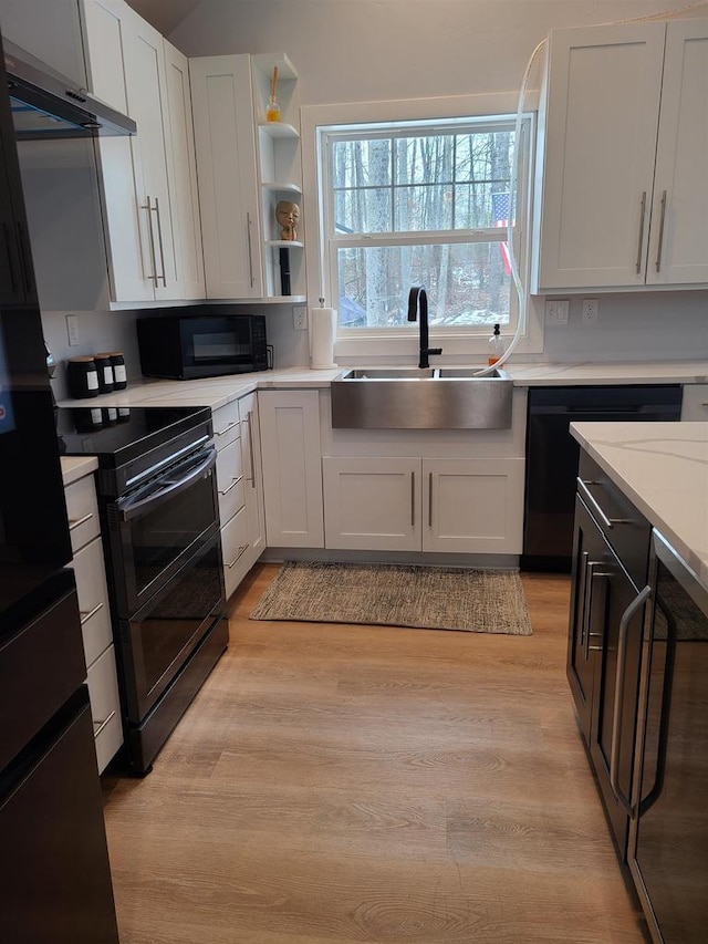 kitchen with sink, white cabinets, light hardwood / wood-style floors, and black appliances