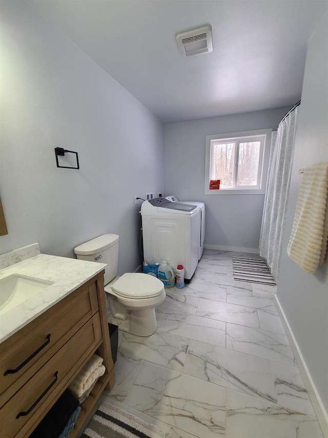 bathroom featuring vanity, washer and dryer, and toilet