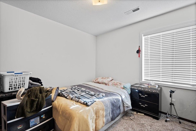 bedroom featuring light colored carpet and a textured ceiling