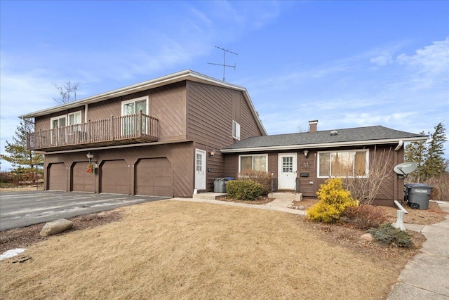 view of front property with a balcony, a garage, and a front lawn