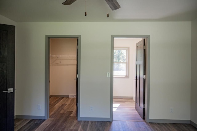 unfurnished bedroom with a walk in closet, dark wood-type flooring, and a closet